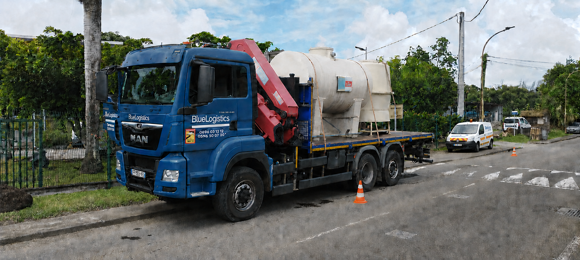 Camion-grue Blue Logistics avec cabine propre transportant un équipement en Martinique